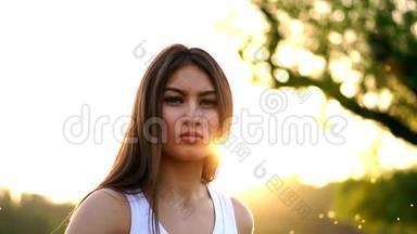 年轻漂亮的女人跑步时在公园听音乐。 带耳机的微笑运动女孩的肖像